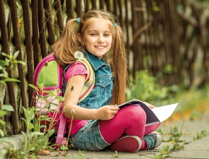 40854476 - little pretty schoolgirl reading a book sitting on the street